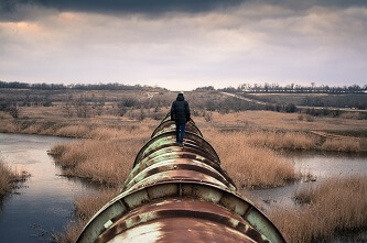 Une homme de dos marchant sur un gazoduc ancien